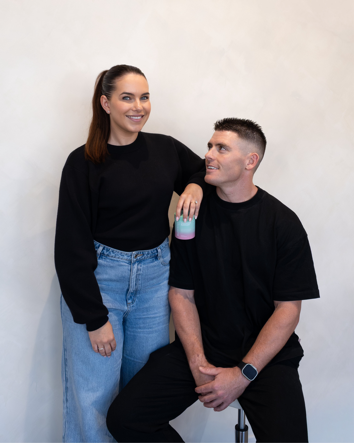 Two people pictured against a white wall